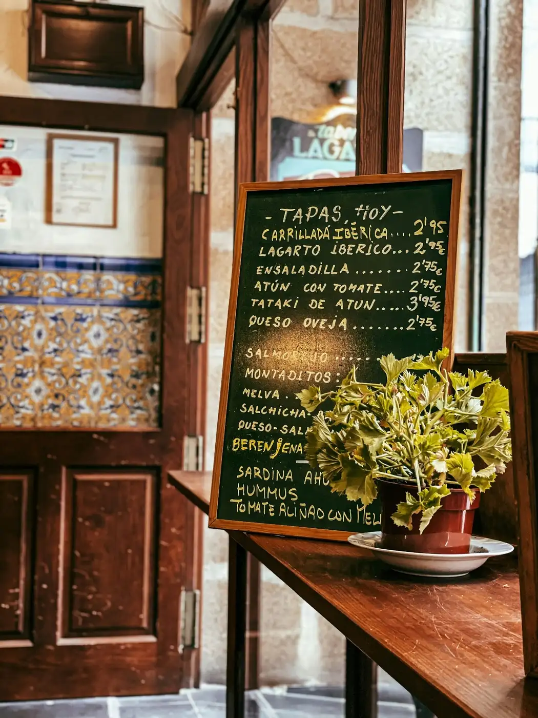 Traditional Spanish bodega entrance with handwritten chalkboard tapas menu and azulejo tiles in Barcelona