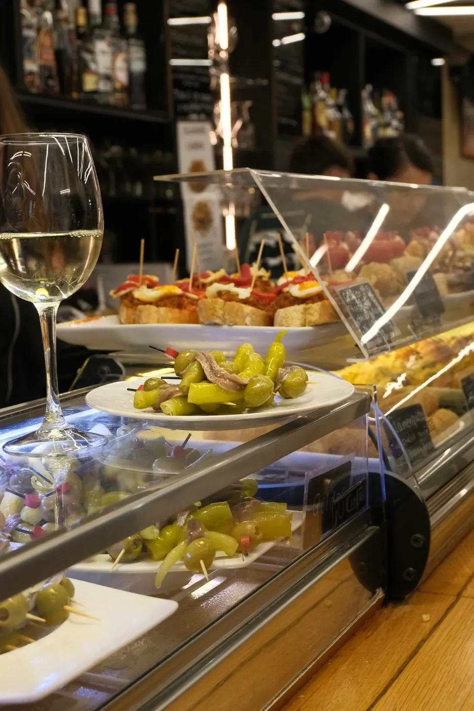 Authentic Barcelona tapas bar counter with pintxos, olives and a glass of white wine