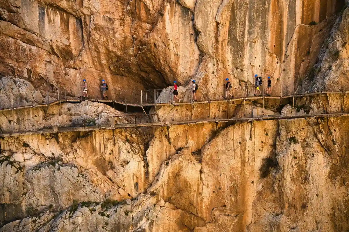 Narrow wooden boardwalk of the Caminito del Rey running along a vertical limestone cliff