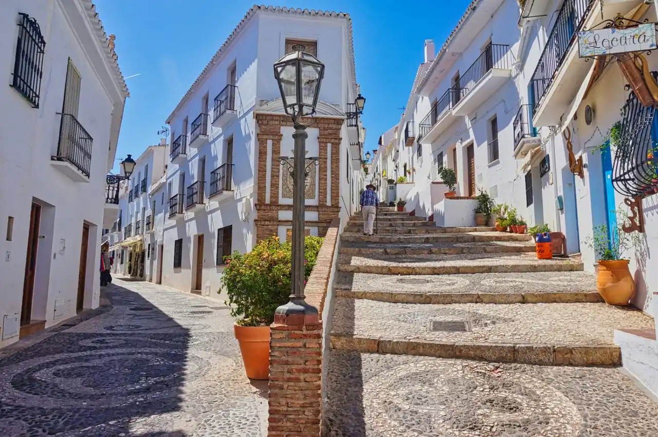 Cobblestone streets and whitewashed houses of Frigiliana old town with traditional Andalusian lampposts and terracotta pots
