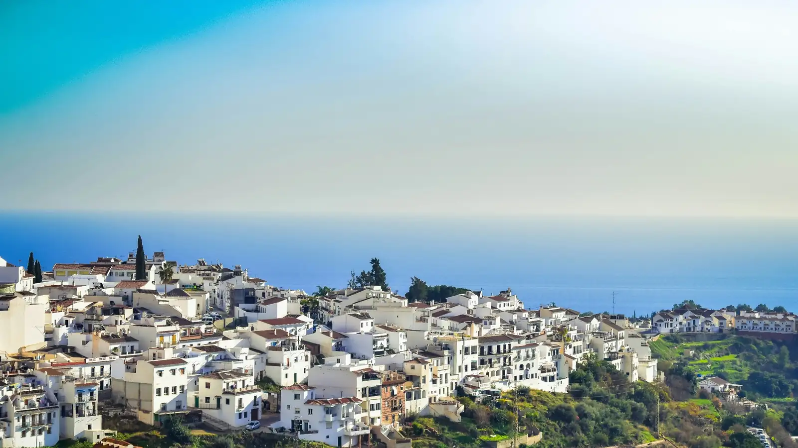 Panoramic view of Frigiliana white village cascading down the Andalusian hills above the Mediterranean Sea
