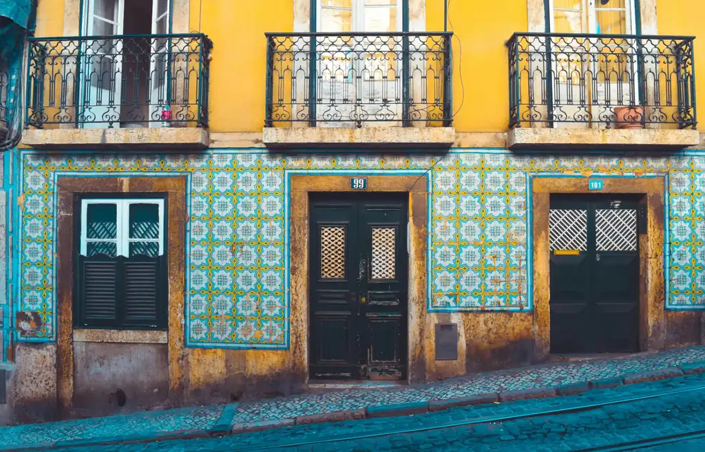Traditional yellow and blue azulejo tile facade with wrought-iron balconies in Alfama, Lisbon