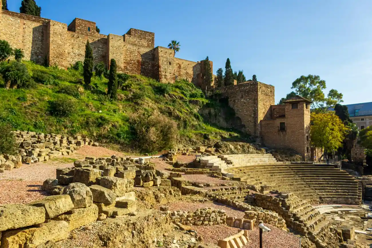 The Alcazaba fortress of Malaga with golden stone walls and views of the city under a dramatic sky
