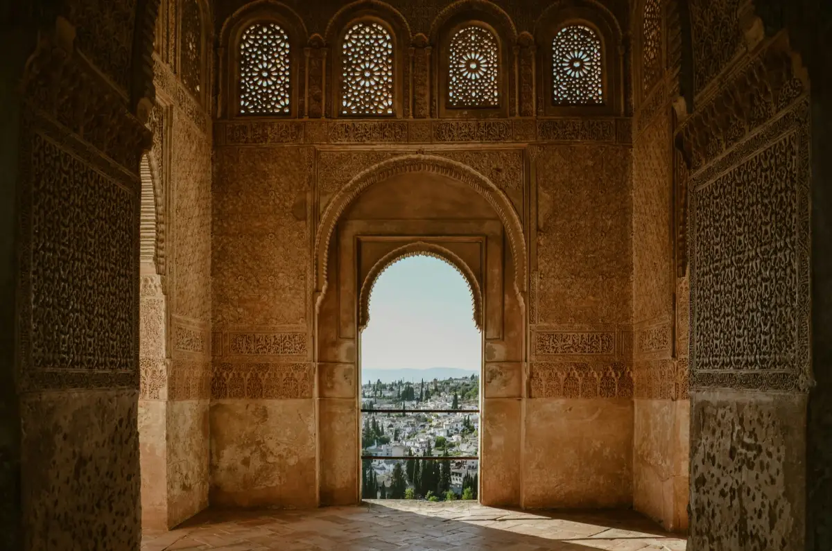 Carved stucco arch inside the Nasrid Palaces of the Alhambra framing a view of Granada's Albaicín