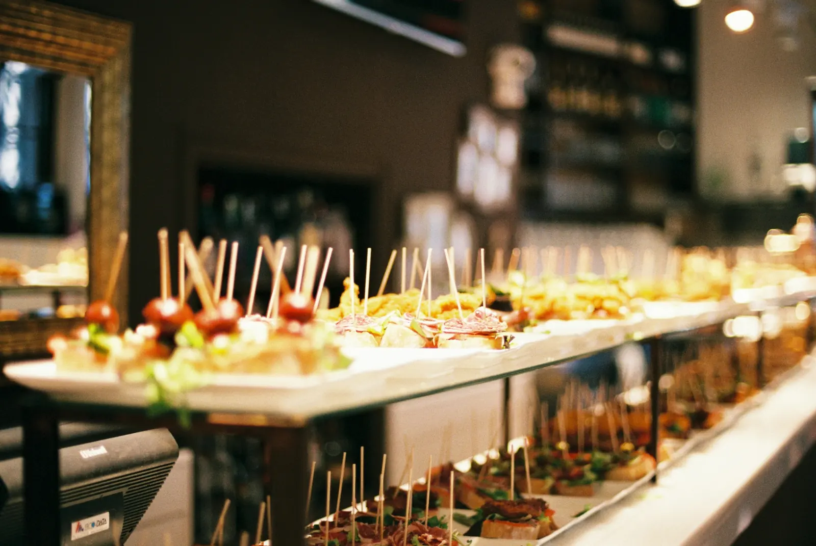 Pintxos vascos bellamente dispuestos y copas de vino blanco sobre una barra de taberna de madera en San Sebastián